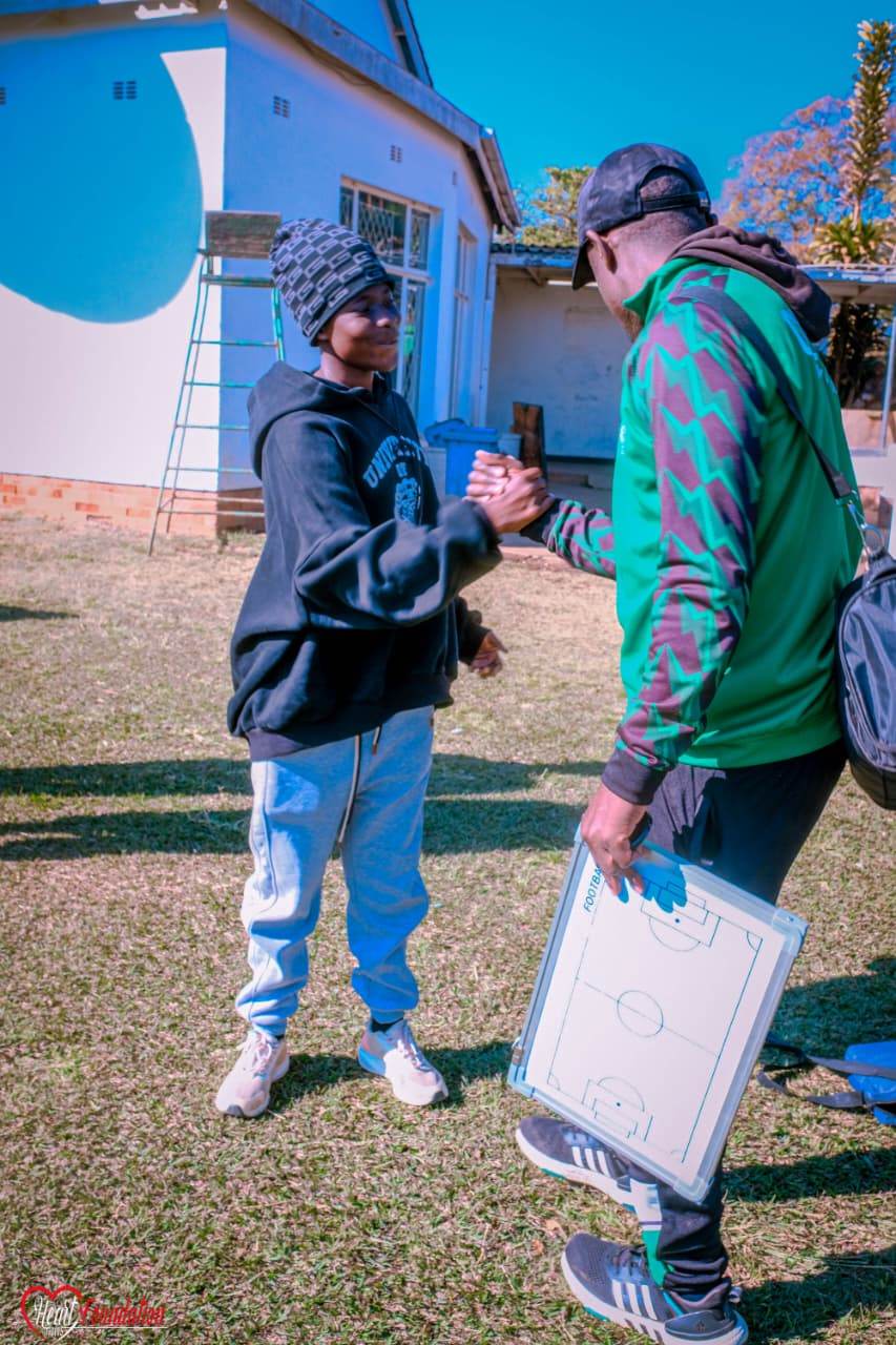 A coach greeting a young player at an academy session