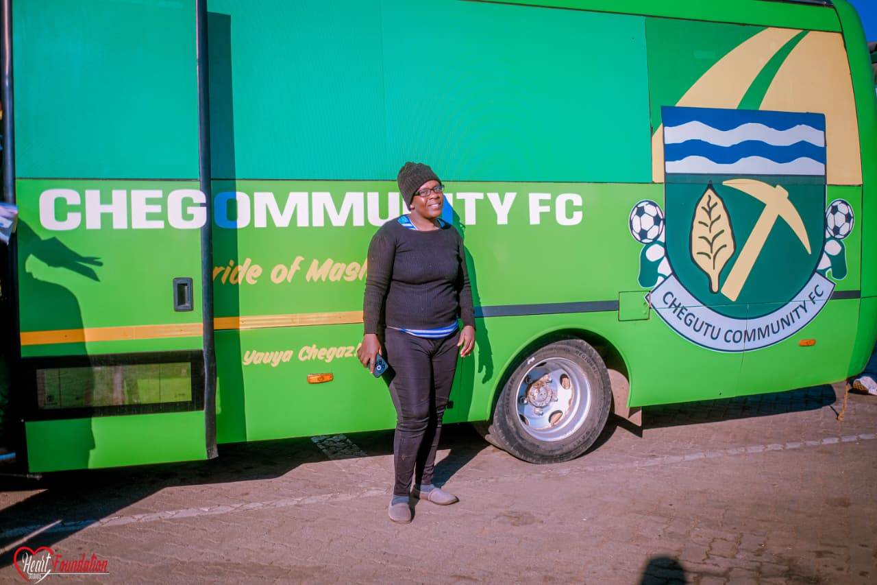A club member standing beside the branded Chegutu Community FC team bus