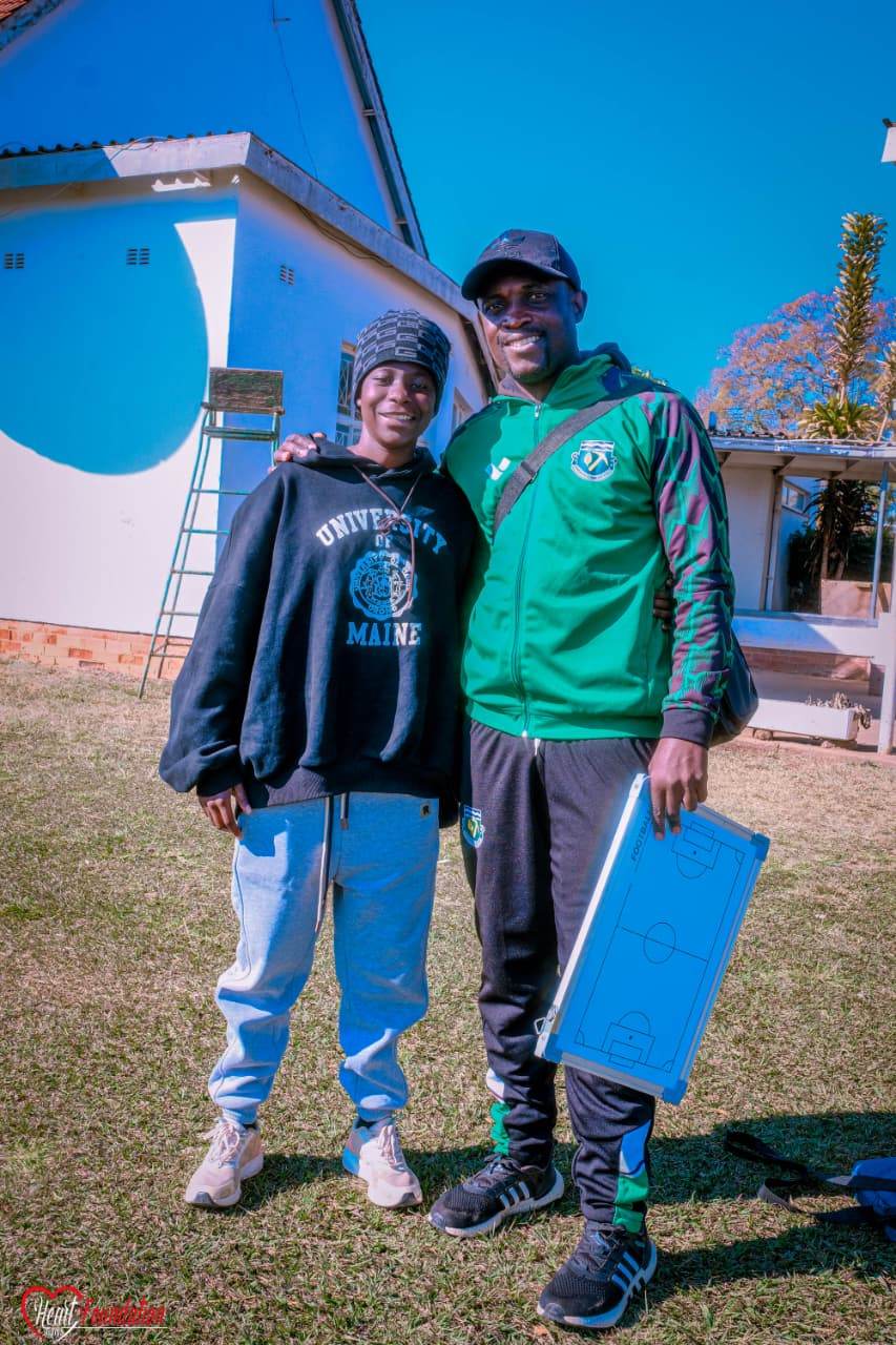 A coach with a tactics board beside a young player