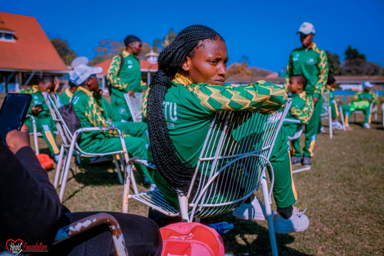 A player resting on the back of a chair beside teammates pitchside