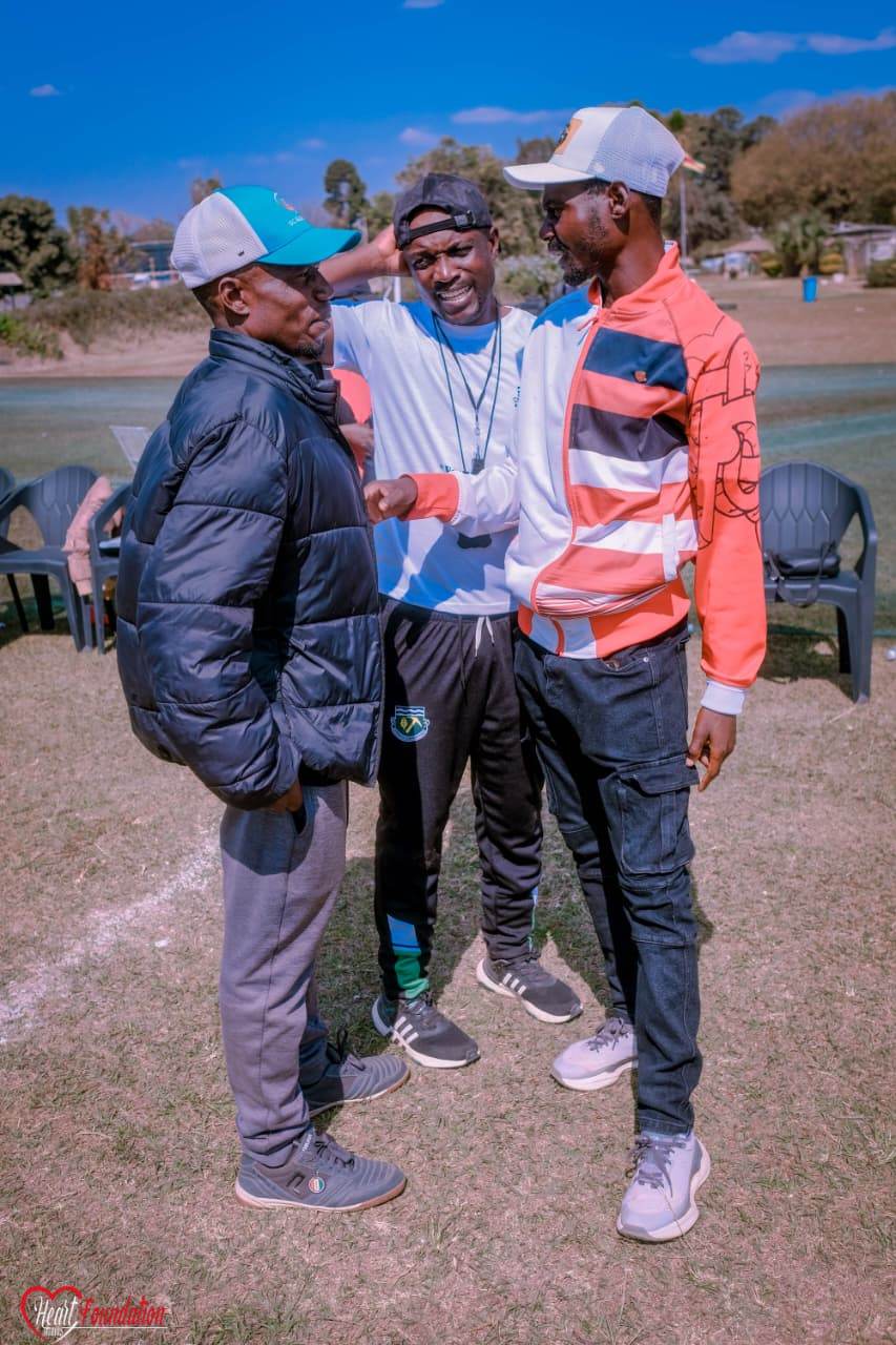 Three club members talking together at the side of the pitch
