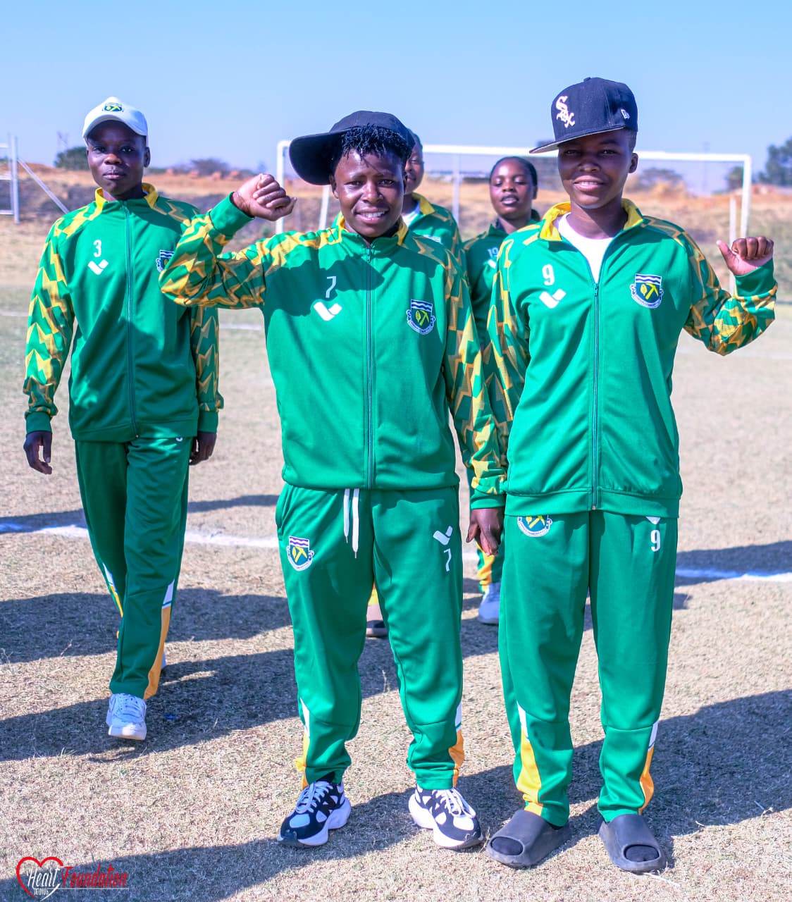 Players in club tracksuits flexing their arms on the pitch